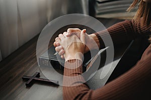 Hands together in prayer to God along with the bible In the Christian concept and religion, woman pray in the Bible on the  table