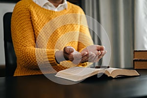 Hands together in prayer to God along with the bible In the Christian concept and religion, woman pray in the Bible on the wooden