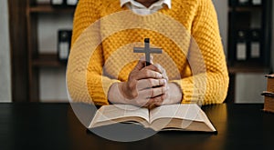 Hands together in prayer to God along with the bible In the Christian concept and religion, woman pray in the Bible on the wooden