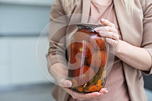 hands tomatoes in a jar on a white background isolation