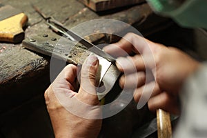 hands and tools of a professional silversmith working on a piece in his traditional workshop, Northern Thailand