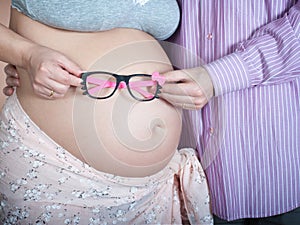 Hands and torso of a pregnant woman and her husband, waiting for a girl