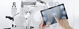 Hands touch screen of digital tablet with ophthalmologist and optometrist icons symbols, ophthalmology and optometry equipment on photo