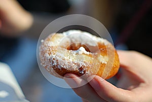 Hands touching covered with sugar donut close up.