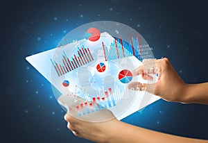 Hands touching a glass-like tablet with charts