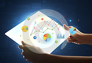 Hands touching a glass-like tablet with charts