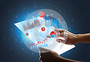 Hands touching a glass-like tablet with charts