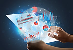 Hands touching a glass-like tablet with charts