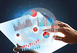 Hands touching a glass-like tablet with charts