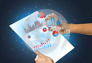 Hands touching a glass-like tablet with charts