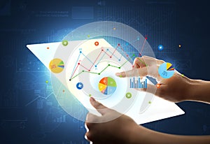 Hands touching a glass-like tablet with charts