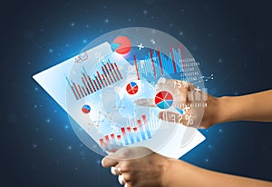 Hands touching a glass-like tablet with charts