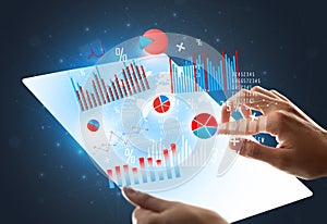 Hands touching a glass-like tablet with charts