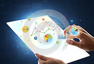 Hands touching a glass-like tablet with charts