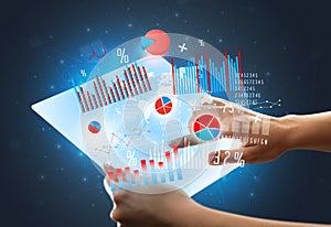 Hands touching a glass-like tablet with charts