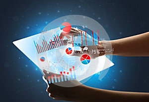 Hands touching a glass-like tablet with charts