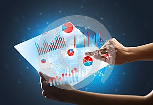 Hands touching a glass-like tablet with charts