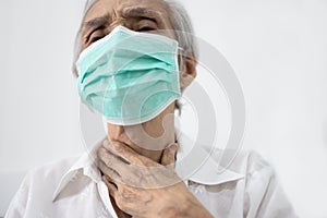Hands touching neck,sick senior female wearing protective face mask,old people has sore throat,cough,hoarseness,swelling,elderly
