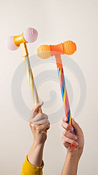 Hands with toy hammers against light background