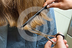 Hands trimming hair with scissors