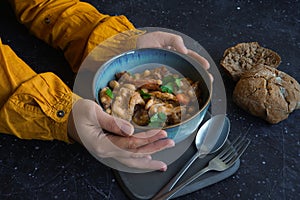 hands with Tripe stew with bread on the black background photo