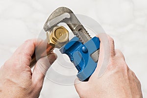 Hands Turning a Brass Nut Using a Pipe Wrench