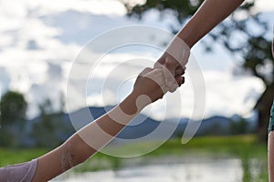Hands of two child holding each other on nature background. concept of mutual assistance and friendship