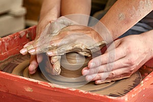 Hands of two people create pot, potter`s wheel. Teaching pottery photo