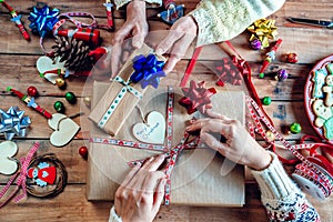 Hands of two women wrapping Christmas gifts
