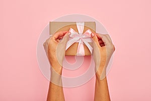 Hands tying pink bow on a present box