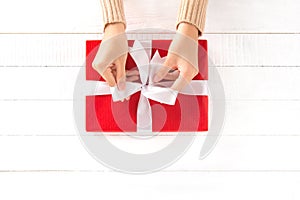 Hands tying ribbon on red gift box