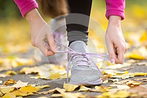 Hands tying trainers shoelaces on the autumn pave