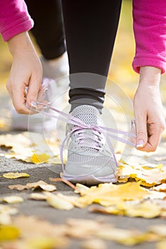 Hands tying trainers shoelaces on the fall pave photo