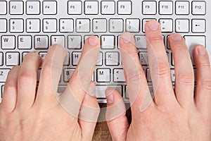 Hands typing on a computer keyboard