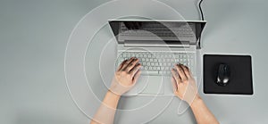 Hands is typing on computer laptop or notebook with mouse and pad on grey background. Studio shot. top eye view