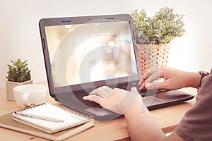 Hands typing laptop with blur background on screen, vintage filtered