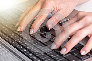 Hands typing on a laptop keyboard, light effect