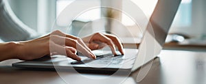 The hands typing on a laptop in a well-lit workspace environment. AI generated image