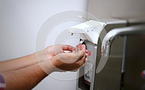 Hands under an automatic wall mounted soap dispenser used I hospital s.