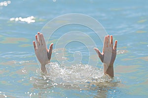 A hands from under the water of a drowning girl, help and urgent rescue of a person during a dangerous swimming, sos