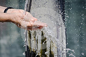 Hands under water fountain