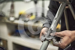 Hands of an unknown person sanding a bicycle frame at his workshop