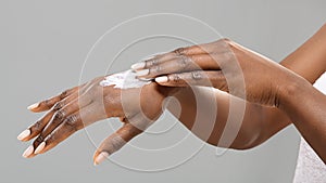 Hands of unrecognizable black woman with applied body lotion.