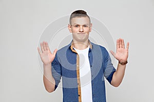 Hands up. Young boy wearing white tshirt and blue shirt looking