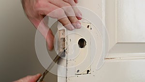 Hands use rusty chisel to make hole for door lock