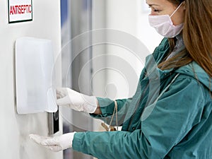 Hands using automatic sanitizer dispenser at supermarket. Disinfectant in a shopping mall during the coronavirus