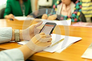 Hands using cell phone with stock money graph with group of business people.