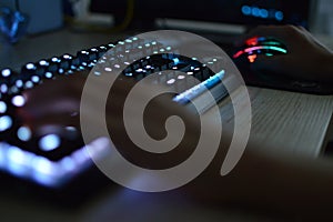 Hands using an illuminated keyboard and mouse. Blurred image.