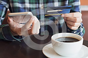Hands using smart phone and holding credit card for shopping online in coffee cafe