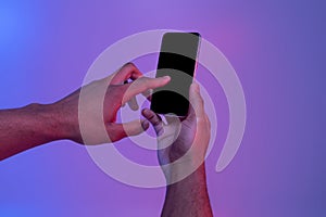 Hands Using Smartphone With Black Screen In Neon Light Over Purple Background